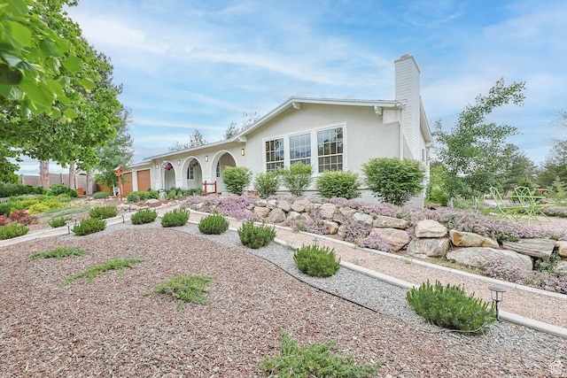 single story home with a chimney and stucco siding