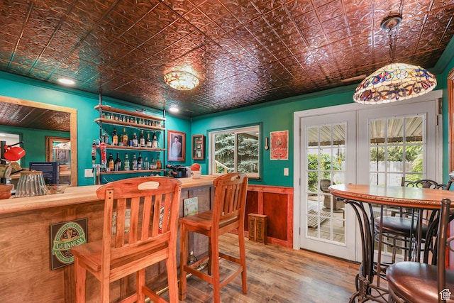 dining area with a dry bar, wood finished floors, an ornate ceiling, and wainscoting