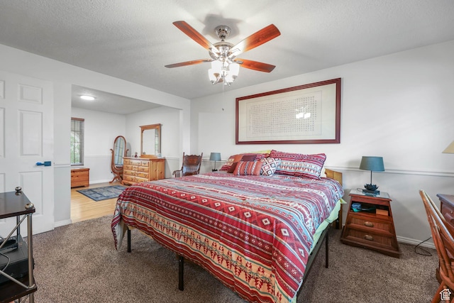 bedroom with carpet flooring, a textured ceiling, a ceiling fan, and baseboards
