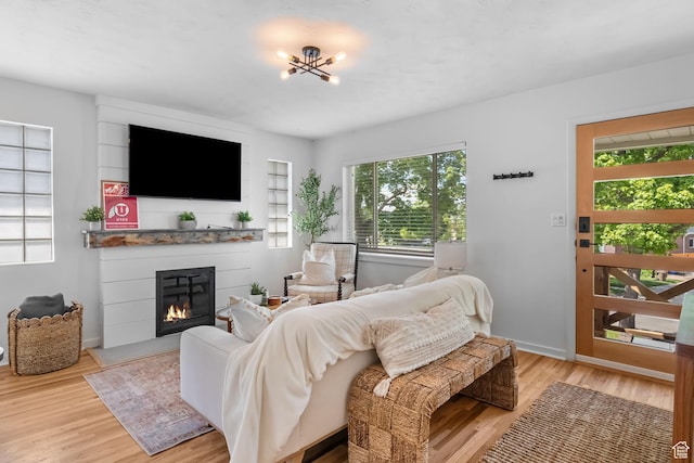 living room with a large fireplace, light wood-style floors, and baseboards