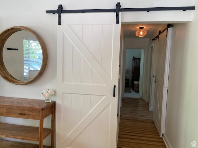 corridor with a barn door and wood finished floors