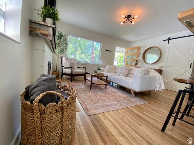 living area with a barn door, light wood-type flooring, and baseboards