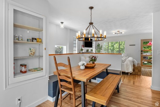 dining area featuring a chandelier, light wood finished floors, baseboards, and breakfast area