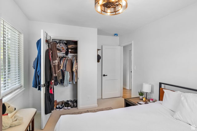 bedroom featuring multiple windows, light carpet, baseboards, and a closet