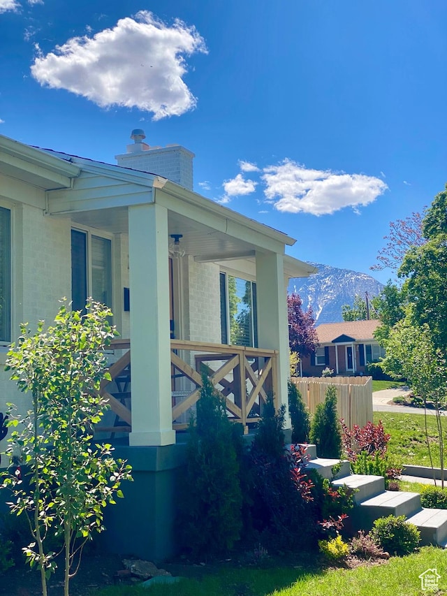 view of side of property with a chimney, a mountain view, and covered porch