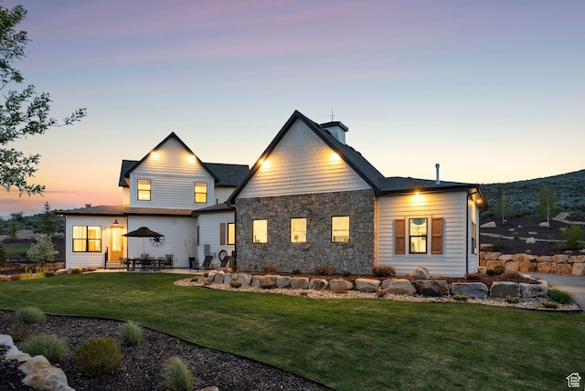 1677 Lambert Ln, Kamas, UT 84036 - back of property featuring a yard, a patio area, stone siding, and a chimney