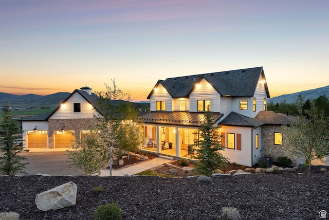 1677 Lambert Ln, Kamas, UT 84036 - rear view of house featuring a porch, concrete driveway, a garage, central air condition unit, and a mountain view