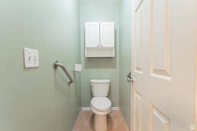 bathroom with toilet, baseboards, and tile patterned flooring