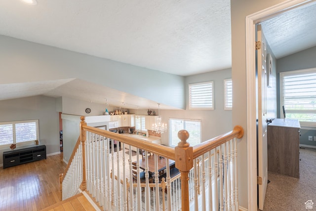 corridor featuring an upstairs landing, plenty of natural light, wood-type flooring, and a textured ceiling
