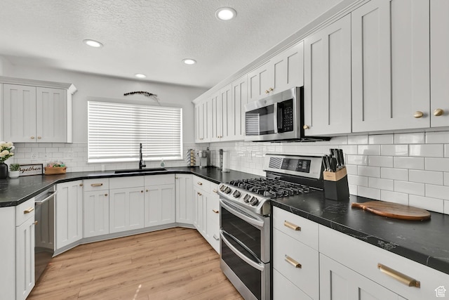 3553 N Willow Creek Ln E, Eden, UT 84310 - kitchen featuring appliances with stainless steel finishes, a sink, dark countertops, recessed lighting, and light wood finished floors