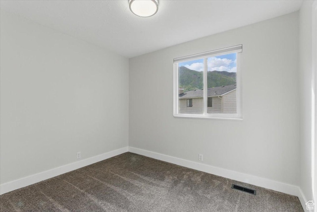 unfurnished room with dark colored carpet and baseboards