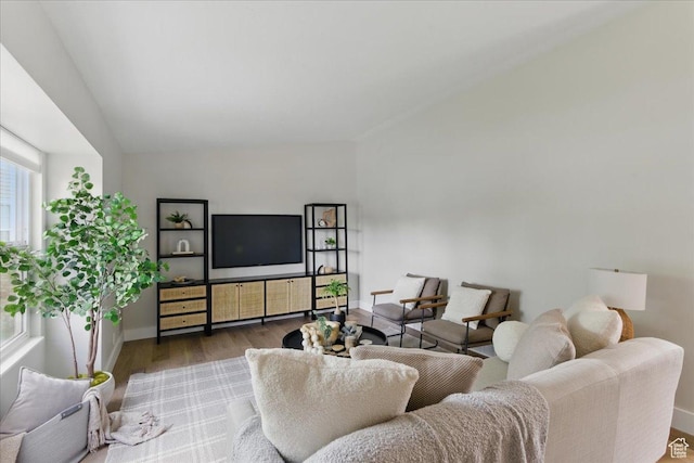 living room with wood finished floors, baseboards, and vaulted ceiling