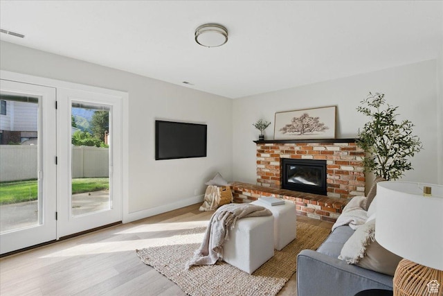living area with light wood finished floors, a fireplace, and baseboards