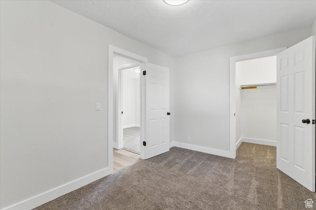 unfurnished bedroom with carpet floors, baseboards, a walk in closet, and a closet