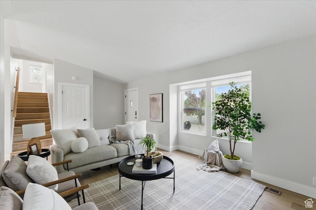 living area featuring stairway, baseboards, and light wood-style flooring