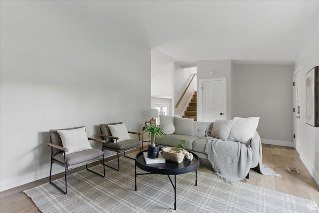 living area with stairway, light wood-style floors, and baseboards