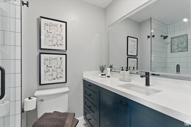 bathroom with a tile shower, toilet, vanity, and baseboards