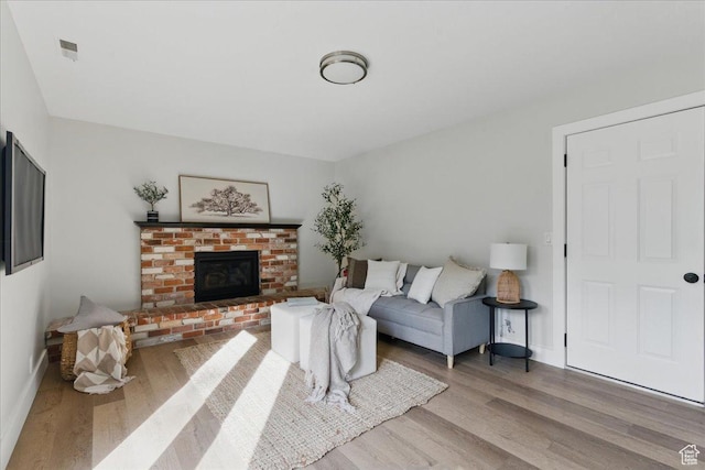 living room with wood finished floors, baseboards, and a fireplace
