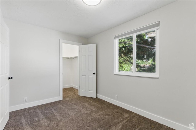 unfurnished bedroom with carpet flooring, baseboards, a spacious closet, and a closet