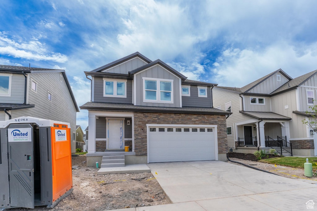 3747 W 950 N Unit 224, Lehi, UT 84043 - view of front of house featuring board and batten siding, an attached garage, concrete driveway, stone siding, and covered porch