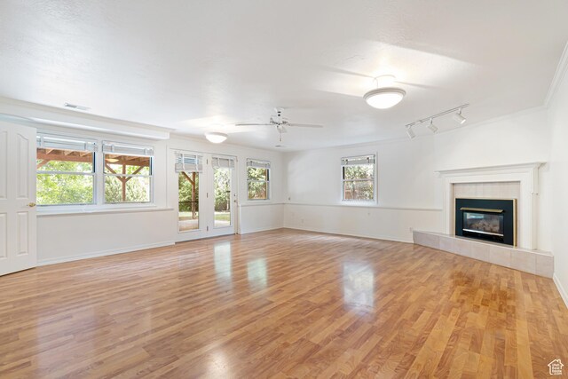 4115 Edgehill Dr, Ogden, UT 84403 - unfurnished living room featuring light wood-style floors, a ceiling fan, a tiled fireplace, baseboards, and track lighting