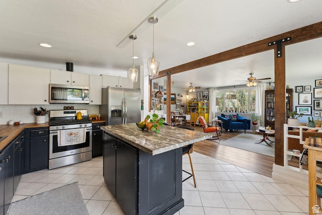 32 S Kingdon Ln E, North Salt Lake, UT 84054 - kitchen with stainless steel appliances, a center island, ceiling fan, open floor plan, and light tile patterned floors