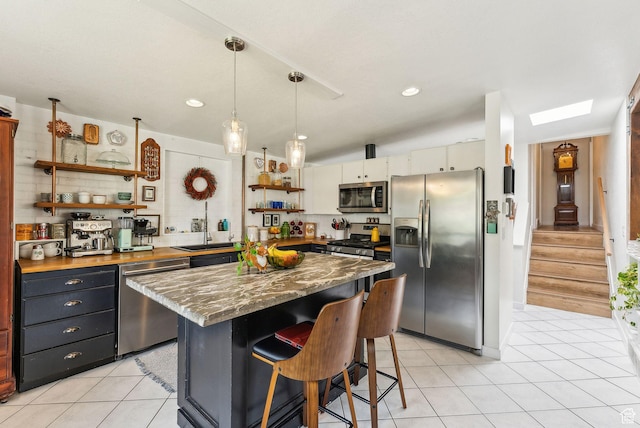 32 S Kingdon Ln E, North Salt Lake, UT 84054 - kitchen featuring appliances with stainless steel finishes, open shelves, light tile patterned flooring, a kitchen bar, and a center island