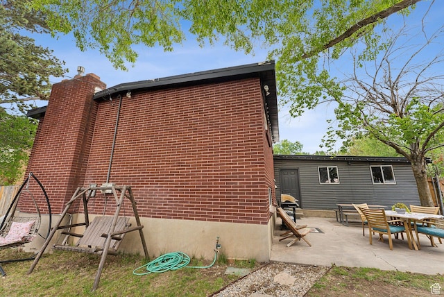 32 S Kingdon Ln E, North Salt Lake, UT 84054 - back of house featuring a chimney, a patio, and brick siding