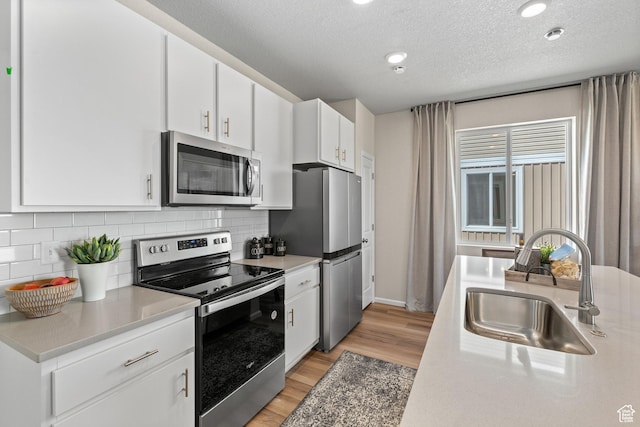354 N Colonnade Rd Unit 987, Saratoga Springs, UT 84045 - kitchen featuring stainless steel appliances, a sink, light wood-type flooring, backsplash, and a textured ceiling
