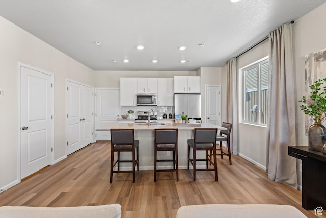 354 N Colonnade Rd Unit 987, Saratoga Springs, UT 84045 - kitchen with appliances with stainless steel finishes, a sink, a kitchen breakfast bar, light wood-style flooring, and a kitchen island with sink