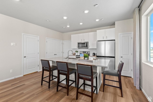 354 N Colonnade Rd Unit 987, Saratoga Springs, UT 84045 - kitchen featuring appliances with stainless steel finishes, a sink, light wood-style flooring, a center island with sink, and white cabinetry