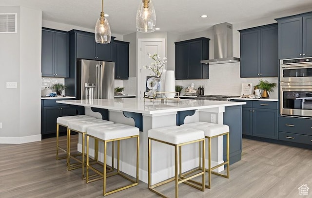 kitchen featuring wall chimney range hood, appliances with stainless steel finishes, light wood-type flooring, tasteful backsplash, and recessed lighting