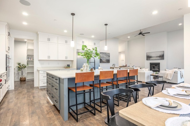 14943 S Auburn Sky Dr Unit 129, Draper, UT 84020 - kitchen with a center island, a ceiling fan, white cabinetry, a breakfast bar, and light countertops