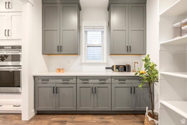 14943 S Auburn Sky Dr Unit 129, Draper, UT 84020 - kitchen featuring gray cabinetry, stainless steel double oven, light countertops, open shelves, and wood finished floors