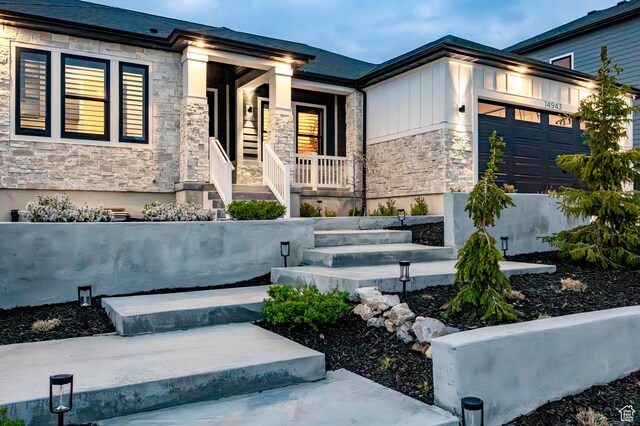 14943 S Auburn Sky Dr Unit 129, Draper, UT 84020 - view of front of house featuring stone siding, a porch, and an attached garage