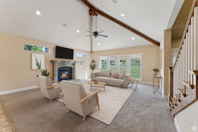 living room with beam ceiling, a ceiling fan, stairway, a glass covered fireplace, and healthy amount of natural light