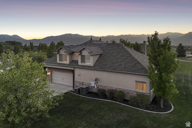 view of front facade featuring stucco siding, stone siding, central AC unit, and a mountain view