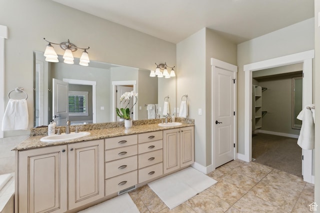 bathroom with double vanity, a walk in closet, and tile patterned flooring