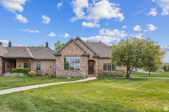 view of front facade featuring stone siding, stucco siding, a front yard, and a shingled roof