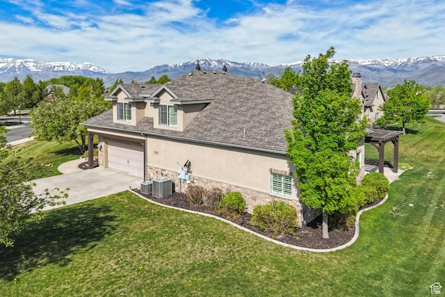 view of home's exterior with stucco siding, stone siding, concrete driveway, and a mountain view