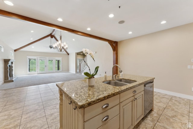 kitchen with a sink, cream cabinets, stainless steel dishwasher, open floor plan, and light tile patterned floors