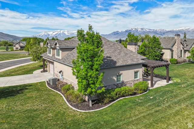 view of home's exterior with stucco siding, stone siding, central air condition unit, and a mountain view