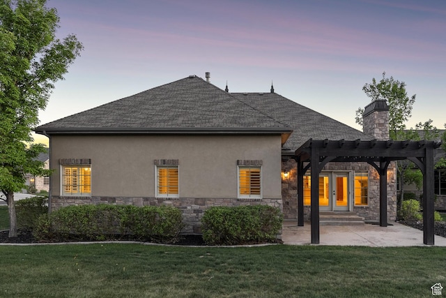back of property featuring stone siding, a lawn, and stucco siding