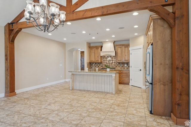 kitchen featuring premium range hood, arched walkways, recessed lighting, tasteful backsplash, and light stone counters