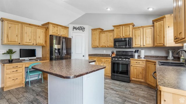 kitchen featuring appliances with stainless steel finishes, a sink, lofted ceiling, dark countertops, and light wood-style floors