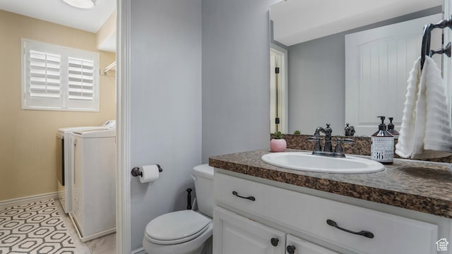 bathroom with washing machine and clothes dryer, toilet, vanity, and baseboards