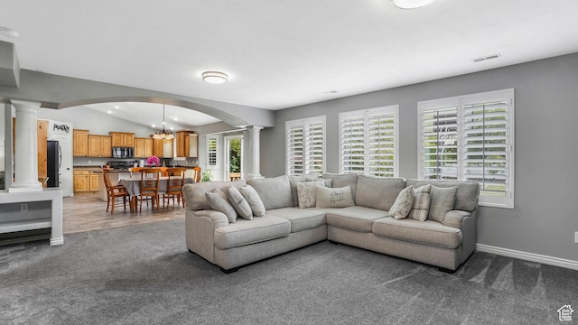 living area with ornate columns, arched walkways, carpet floors, lofted ceiling, and a chandelier