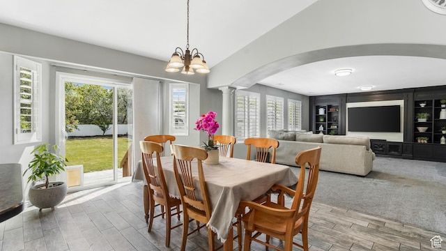 dining space with arched walkways, ornate columns, wood finished floors, plenty of natural light, and vaulted ceiling