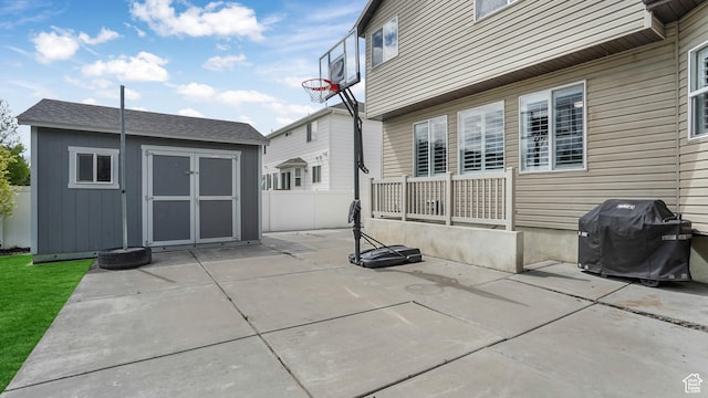 view of patio featuring a storage shed, an outdoor structure, a grill, and fence