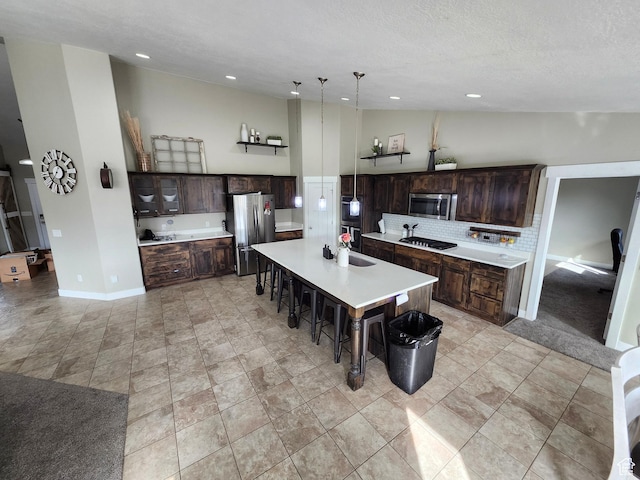 9362 N Sunnyvale Dr, Eagle Mountain, UT 84005 - kitchen with appliances with stainless steel finishes, a kitchen bar, tasteful backsplash, dark brown cabinets, and light countertops